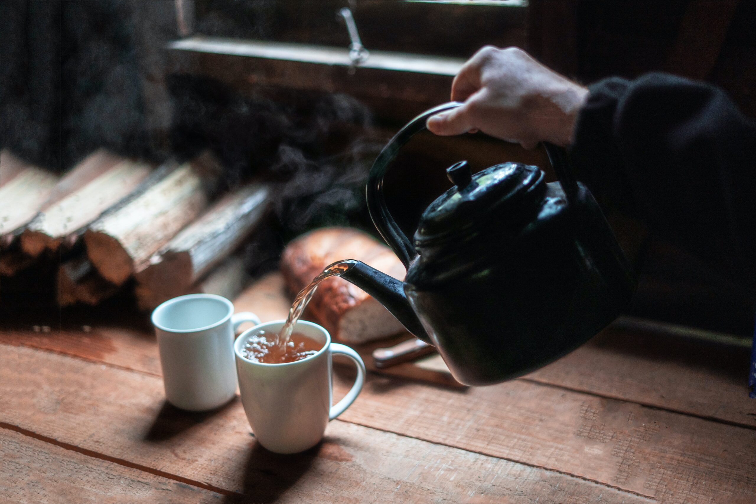 Eine Person gießt Tee in eine Tasse ein